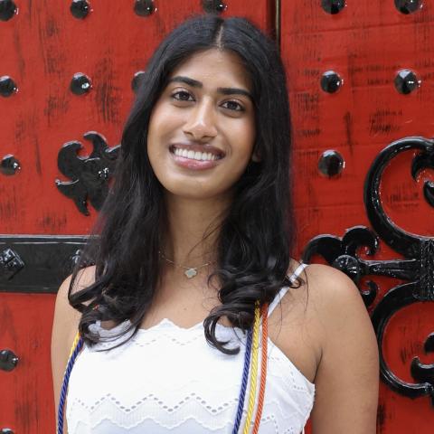 A headshot of Sanjana smiling in front of a red door